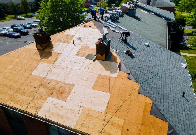 A roofer inspecting a roof for signs of damage.