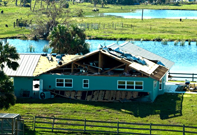 Close-up view of a damaged roof with missing shingles and exposed underlayment, illustrating the impact of severe wind damage.
