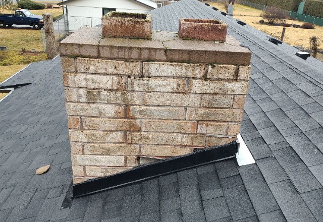 The base of a chimney with new metal flashing installed, showing quality roof repair work in a residential area of Nine Mile Falls, WA.