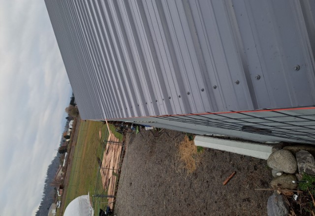 View of almost finished metal roof from a skewed angle with the countryside visible in the background, installed by insulation company in Spokane
