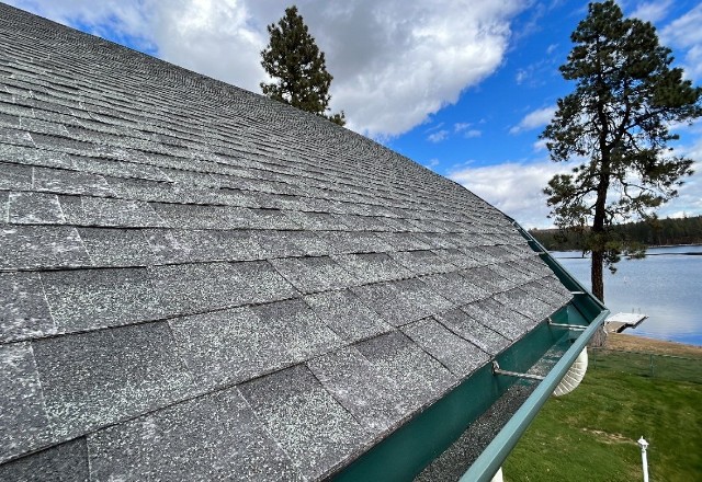 Close-up view of worn asphalt shingle roof in Spokane Valley, showcasing granule loss and color fading