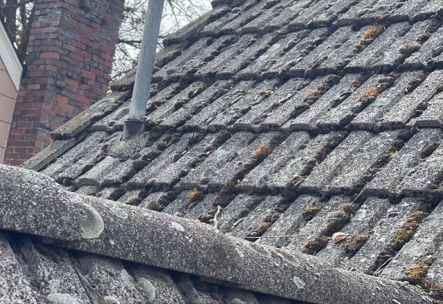 Close-up of an old cedar shake roof with visible moss growth, likely in need of service by a roofing company in Spokane