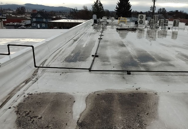 Flat commercial roof with standing water and dirty streaks, indicating poor drainage and potential for water damage issues