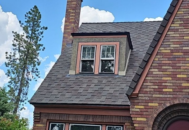 Historic home with a partially replaced roof, demonstrating the careful workmanship of a roofing contractor in Spokane