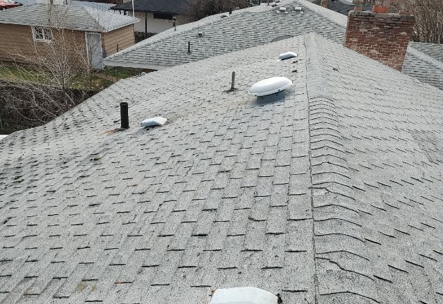 Spokane Valley home showcasing a worn-out roof with curled and missing shingles, indicating a need for roof replacement services