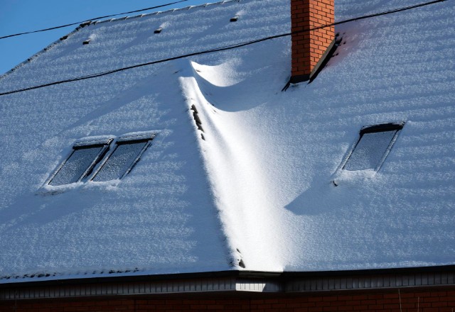 The snow covering indicates recent snowfall or accumulation over time, which can be typical in regions with cold winters. It's important for roofs to be properly designed to handle such snow loads and regular checkups to monitor roof condition.