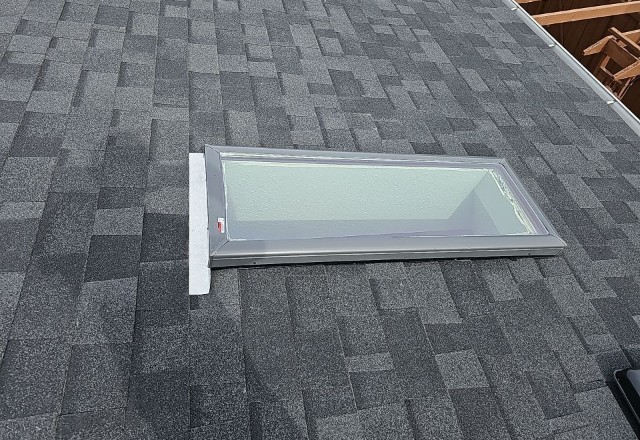 After replacement: A new, clean skylight installed on the same asphalt shingle roof, reflecting a successful window replacement.