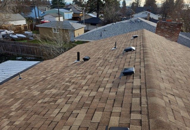 Roof replacement finished in Spokane Valley, with a completed new brown shingle installation over an old roofing layer