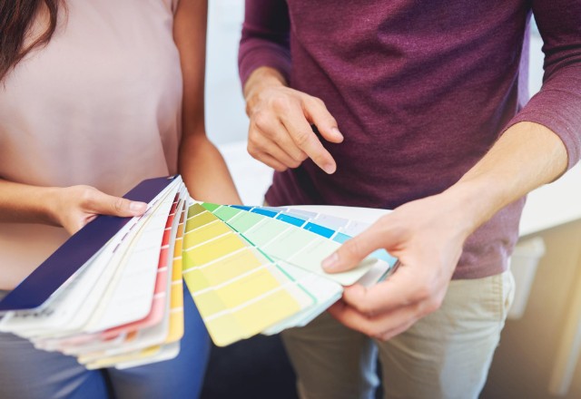 Cropped view of a couple examining a wide array of color swatches, indicative of the personalized painting services offered by painting contractors in Spokane.