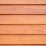 Close-up texture of wooden siding boards in a warm orange hue, a popular choice for siding color in Spokane's residential areas