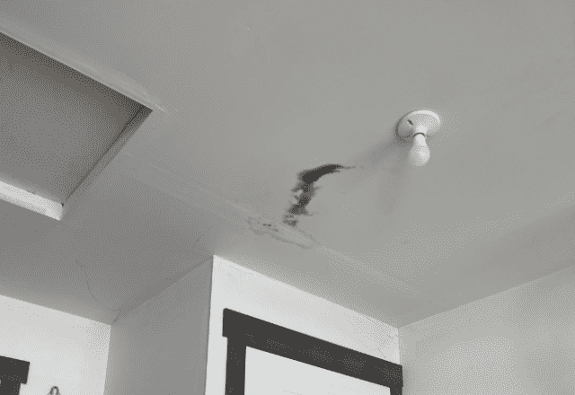 Roof repair Rathdrum - interior view of a ceiling with water stains and damage near a light fixture, suggesting a potential roof leak
