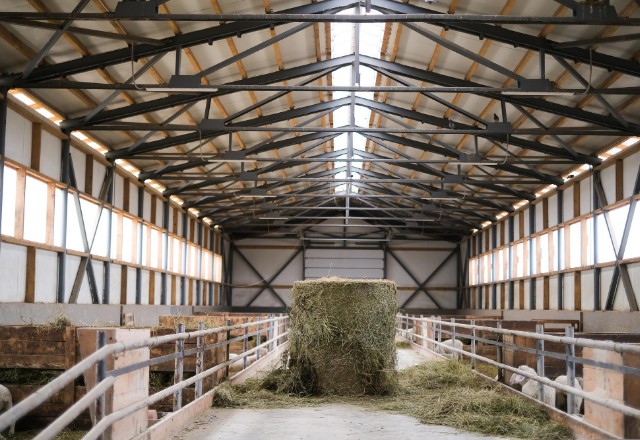 Interior of a Spokane pole building dedicated to agriculture, with a large hay bale centered in the walkway, constructed by skilled pole building contractors in Spokane