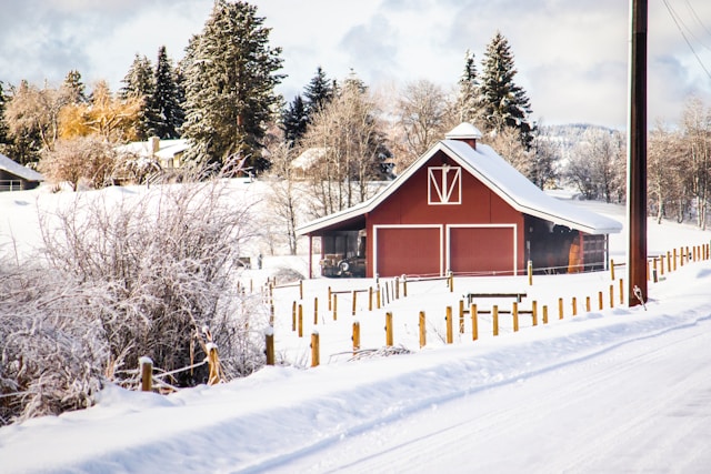 A picturesque red pole building in a snowy Spokane landscape, illustrating the robust and weather-resistant construction by Spokane pole builders