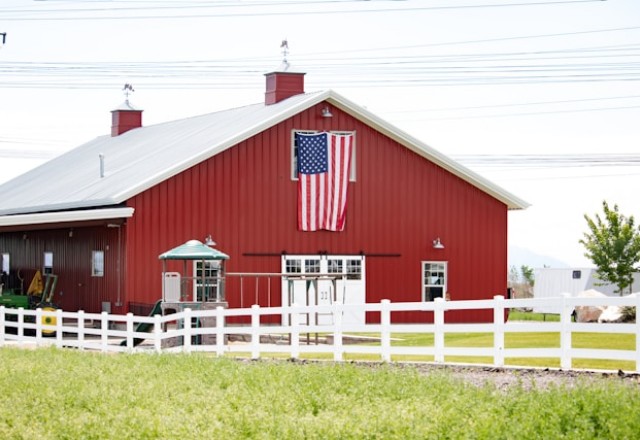 Spacious red pole barn adorned with an American flag, exemplifying the patriotic spirit of Spokane's pole building companies