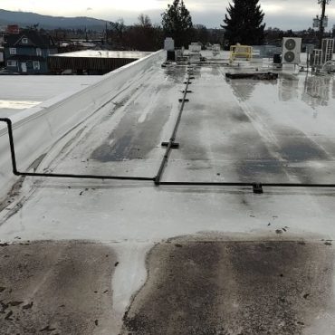 Flat commercial roof with standing water and dirty streaks, indicating poor drainage and potential for water damage issues