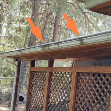 Image shows a weathered gutter on a wooden structure with visible cracks and stains, indicating potential issues for a Spokane gutter repair contractor to address.