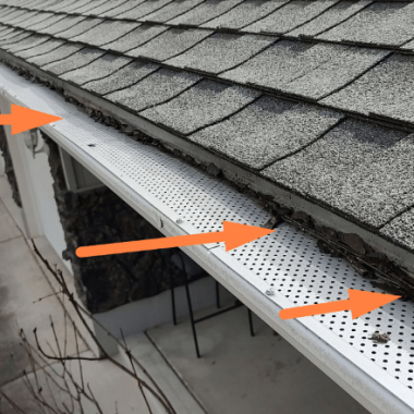 Gutter filled with debris like leaves and pine needles against a shingled roof, showcasing cleaning needs for a Spokane gutter service company